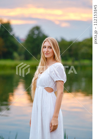 Cute woman standing by the river at sunset Cute woman standing by the river at sunset 112153845
