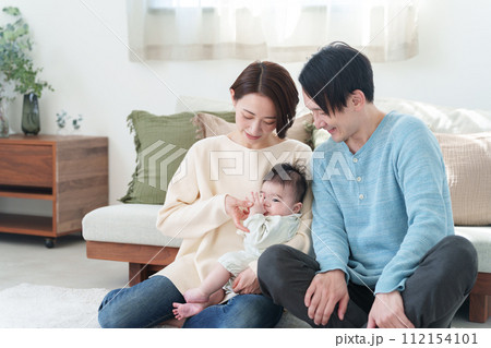 笑顔の家族と指しゃぶりする赤ちゃん 112154101