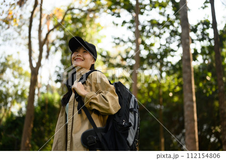 Relaxed young woman with backpack trekking in forest and enjoying nature 112154806