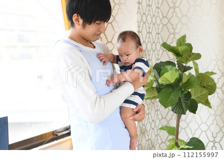 乳幼児を抱っこするアジア人の男性保育士 112155997