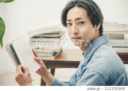 部屋で読書をする若い男性 112156369