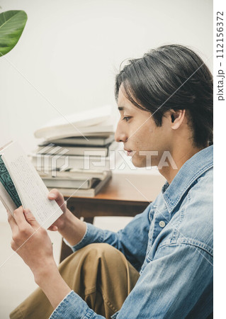 部屋で読書をする若い男性 112156372
