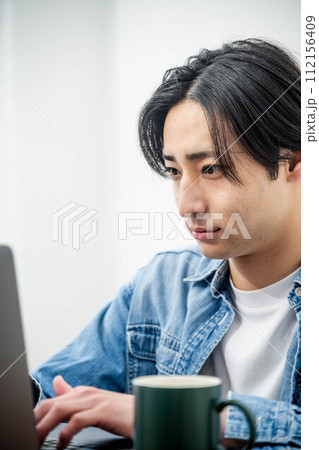 家でパソコンを前に考える若い男性 112156409