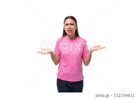 young slim brunette woman in pink basic t-shirt has doubts on white background with copy space 112156611