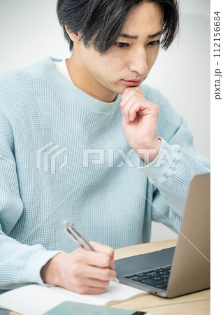 リビングでパソコンをいじっている若い男性 リビングでパソコンをいじっている若い男性 112156684
