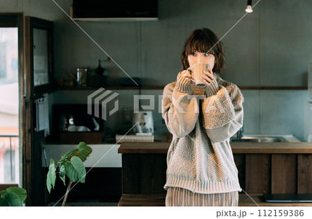 カウンターで温かい飲み物を飲む女性 カウンターで温かい飲み物を飲む女性 112159386