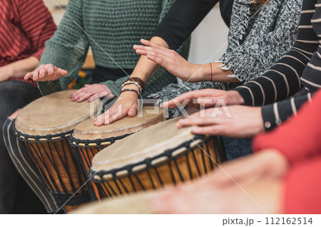 Group of people playing drums during a music therapy lessons, jembe drum, drumming concept Group of people playing drums during a music therapy lessons, jembe drum, drumming concept 112162514