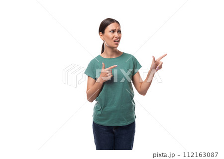 active smiling young caucasian brunette woman in a green t-shirt points with her hand at the space active smiling young caucasian brunette woman in a green t-shirt points with her hand at the space 112163087