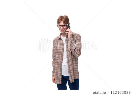 young handsome red-haired guy in a plaid shirt speaks on the phone young handsome red-haired guy in a plaid shirt speaks on the phone 112163088