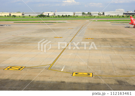 Aerial view of a commercial airport runway with marking on taxiway. 112163461