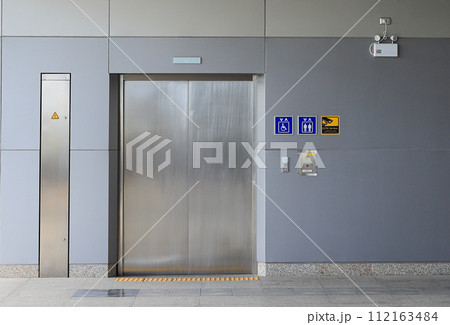 Hallway with LCD screen floor stand, Modern steel elevator cabins, closed elevator doors. Hallway with LCD screen floor stand, Modern steel elevator cabins, closed elevator doors. 112163484