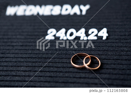 Rings of the newlyweds on the background of a Beautiful date for the wedding 04.24.2024 on a black lettobord 112163808