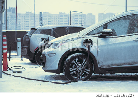 Charging electric car on the street. Electric car in snow on charging spot, cold conditions. download image 112165227