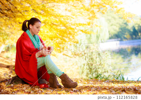 thoughtful girl in the autumn park enjoying hot drink thoughtful girl in the autumn park enjoying hot drink 112165828