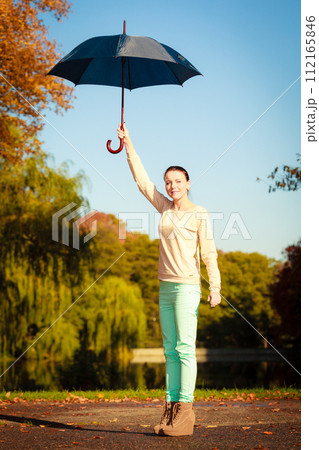 Girl walking with umbrella in autumnal park Girl walking with umbrella in autumnal park 112165846