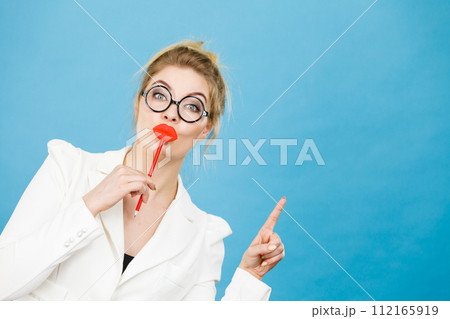 woman holds fake lips on stick pointing at copy space woman holds fake lips on stick pointing at copy space 112165919