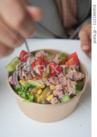 spoon pick tuna salad from a bowl on table  112166958