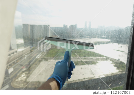 Rubber squeegee cleans a soaped window. Rubber squeegee cleans a soaped window. 112167002