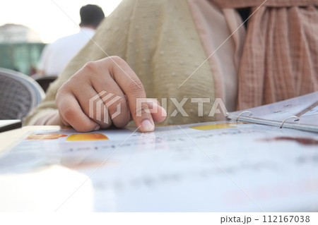 women hand reading a food menu at cafe. 112167038