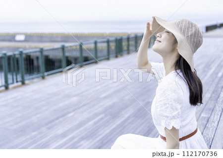 マリーナのウッドデッキでくつろぐ白ワンピースの女性 マリーナのウッドデッキでくつろぐ白ワンピースの女性 112170736