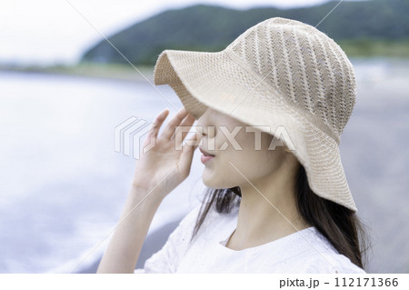 海を眺める麦わら帽子の女性 112171366