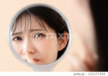 鏡を見て肌の調子が気になる女性 112171784