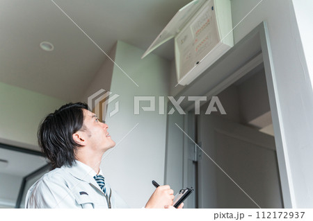 分電盤・配電盤・ブレーカーをチェックする作業着姿の男性ビジネスマン 112172937