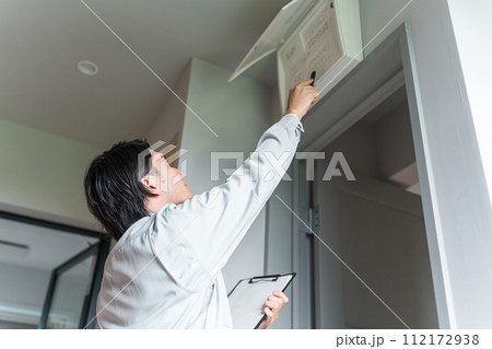 分電盤・配電盤・ブレーカーをチェックする作業着姿の男性ビジネスマン 分電盤・配電盤・ブレーカーをチェックする作業着姿の男性ビジネスマン 112172938