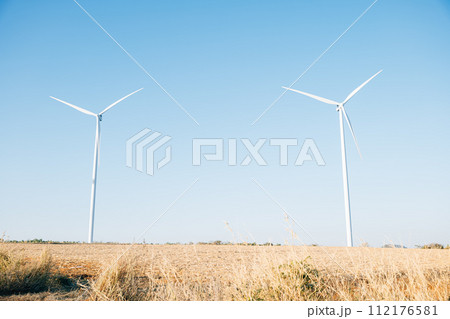 The picturesque scene of wind turbines on a mountain farm spinning in harmony with nature. Clean energy technology against a blue sky embracing sustainable development. 112176581