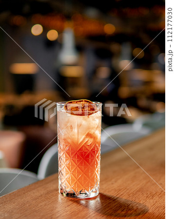 Glass of frozen citrus cocktail with triple sec on bar counter in restaurant interior background, copy space Glass of frozen citrus cocktail with triple sec on bar counter in restaurant interior background, copy space 112177030