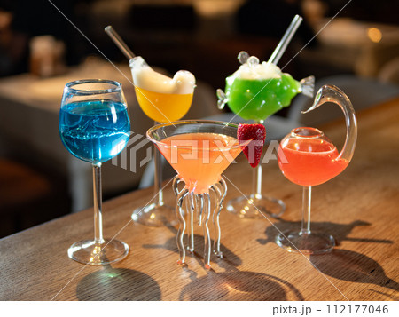 Set of different colorful alcoholic cocktails - margarita, blue lagoon, cosmopolitan and other. Set of various classic cocktails on bar counter background. Selection cocktails and soft drinks 112177046