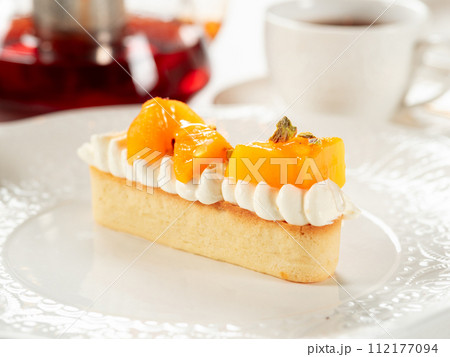 Persimmon tart with whipped cream. Delicious soft and creamy tart with fresh sweet persimmons on white plate on restaurant table background. Dessert idea with persimmons fruit 112177094