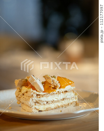 Puff layered cake with cream of cream-cheese, decorated fresh persimmons. Delicious and eye-catching piece of layered cake decorated orange persimmons Puff layered cake with cream of cream-cheese, decorated fresh persimmons. Delicious and eye-catching piece of layered cake decorated orange persimmons 112177097