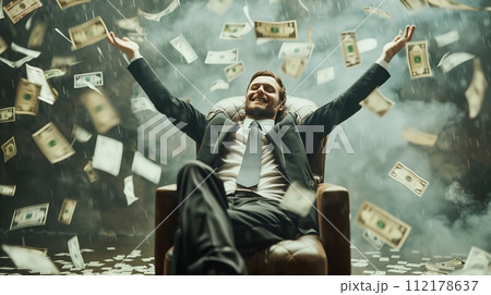 Jackpot winner becomes rich, sitting in a chair with a big smile as money rains down on him. 112178637