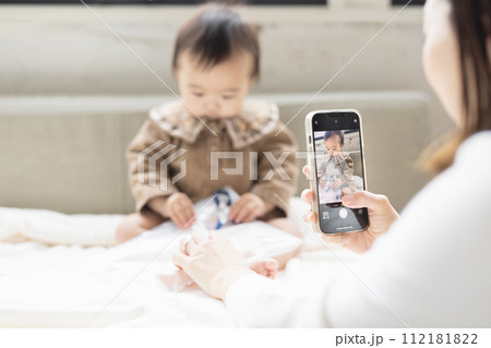 スマホで赤ちゃんの写真を撮る母親 スマホで赤ちゃんの写真を撮る母親 112181822