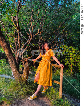 A woman stands by the fence at sunset 112182113