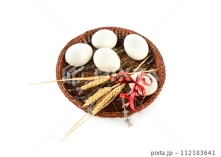 Easter eggs in a wicker basket isolated on a white . 112183641