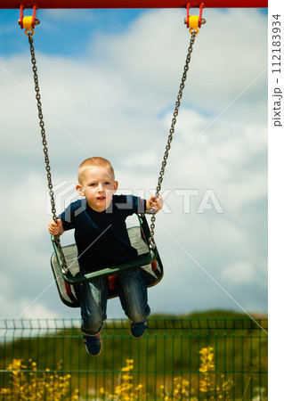 Little blonde boy child having fun on a swing outdoor Little blonde boy child having fun on a swing outdoor 112183934