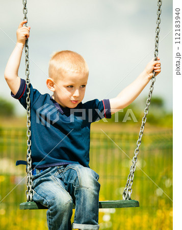 Little blonde boy child having fun on a swing outdoor Little blonde boy child having fun on a swing outdoor 112183940