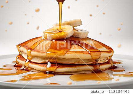 Stack of pancakes with maple syrup and banana slices on top. 112184443