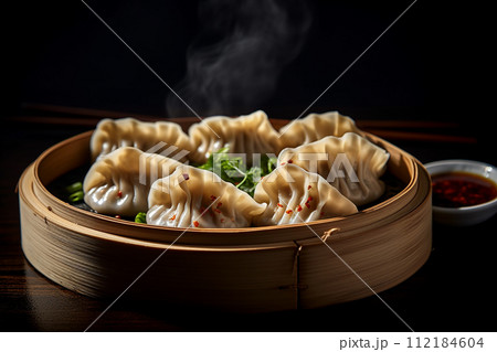Steamed dumplings gyoza with meat in bamboo steamer with soy sauce on the side 112184604