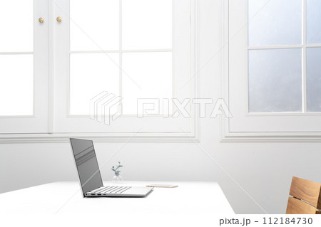 窓際の白いテーブルの上のノートパソコンとスマホ 112184730