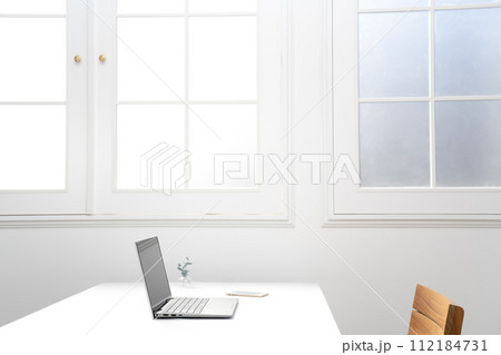 窓際の白いテーブルの上のノートパソコンとスマホ 112184731