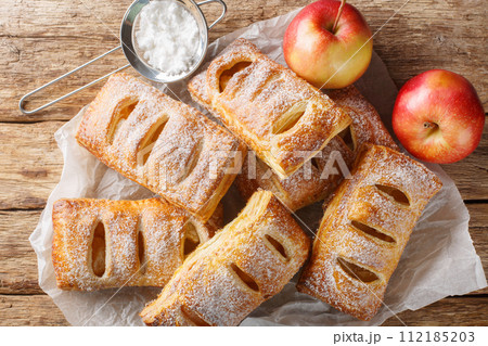 Delicious apple puffs with powdered sugar close-up on paper. Horizontal top view Delicious apple puffs with powdered sugar close-up on paper. Horizontal top view 112185203