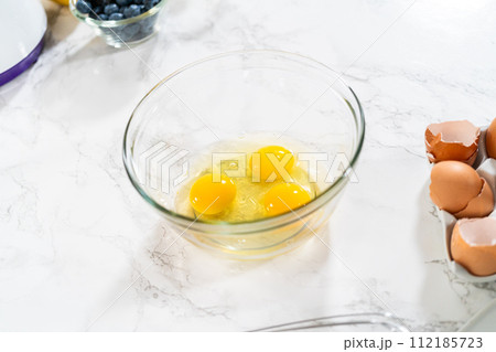Combining ingredients within a glass bowl, skillfully stirring with a whisk to prepare a delicious vanilla bundt cake. Combining ingredients within a glass bowl, skillfully stirring with a whisk to prepare a delicious vanilla bundt cake. 112185723