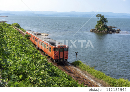 雨晴海岸沿いを走る氷見線の列車 112185943