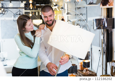 Young family touching floor lamp in the furniture store Young family touching floor lamp in the furniture store 112186202