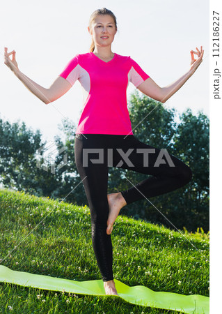 Sportswoman in pink T-shirt is staying and practising meditation 112186227