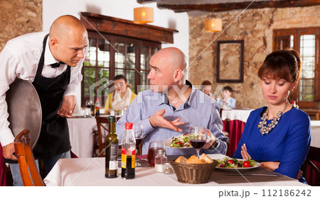 Upset couple complaining to waiter Upset couple complaining to waiter 112186242