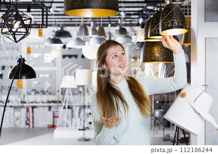 Girl buying plummed lamp in the modern furniture store Girl buying plummed lamp in the modern furniture store 112186244